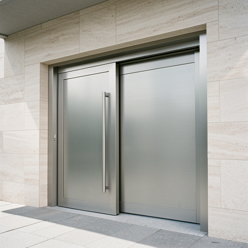 Portail coulissant gain de place pour l’entrée d’une maison, avec un cadre moderne en aluminium sur une façade en pierre claire, vu en lumière naturelle.